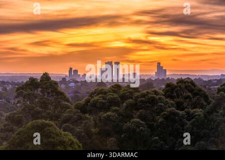 Distant high-rise business towers of Parramatta city CBD at sunset under dramatic orange sky in Australia. Stock Photo