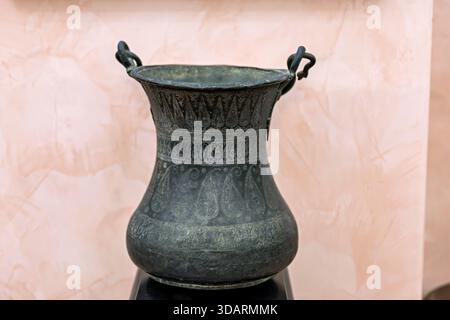 Late medieval Azerbaijani bronze vase with intricate Buta pattern engravings, looped handles, displayed on neutral background. Stock Photo