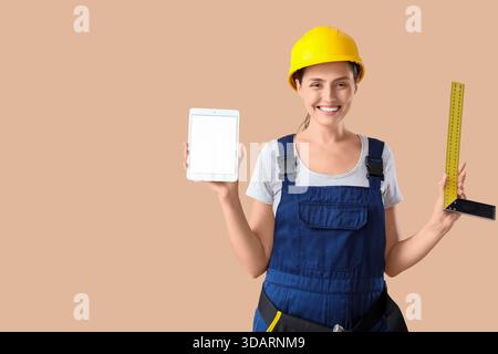 Female builder with blank tablet computer and ruler on beige background Stock Photo