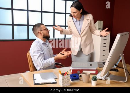 Angry female boss scolding her employee at desk in office Stock Photo