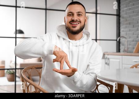 Young man using sign language in kitchen Stock Photo