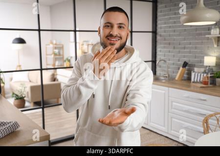 Young man using sign language in kitchen Stock Photo
