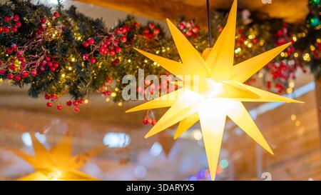 Large glowing Christmas star hanging among festive garlands with red berries and warm lights, creating a cozy and cheerful holiday decoration in a win Stock Photo