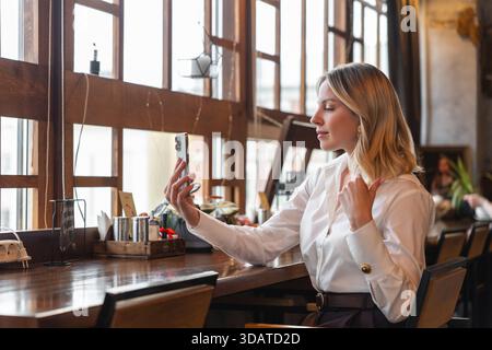 Woman taking selfie at cafe. Connecting with audience. Stock Photo