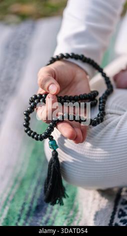 Person meditating holding mala beads and prayer tassel Stock Photo
