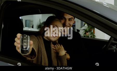 Happy young couple sitting in a new car and talking to a car salesman Stock Photo