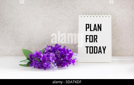 Plan for today, the text is written on a notebook, next to the flower Stock Photo