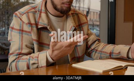 Close-up of two people discussing notes and documents on a cafe table Stock Photo