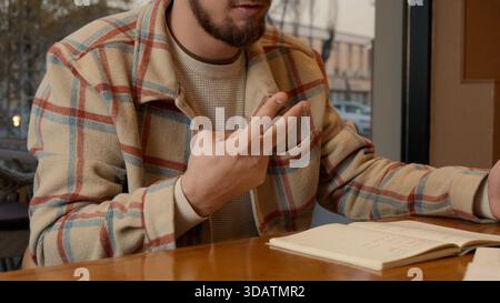Close-up of two people discussing notes and documents on a cafe table Stock Photo