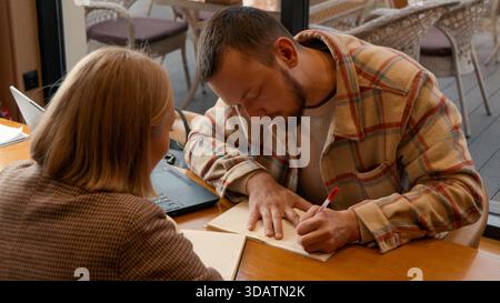 Two students focused on documents and making notes together in a cafe Stock Photo