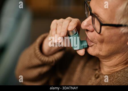 Senior Caucasian Man Using Inhaler While Sitting in Nursing Home Stock Photo