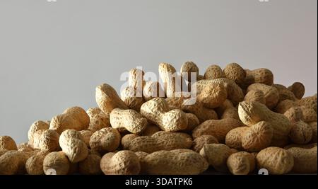 Detail of a pile of peanuts in shell isolated on a gray background. Front view. Stock Photo