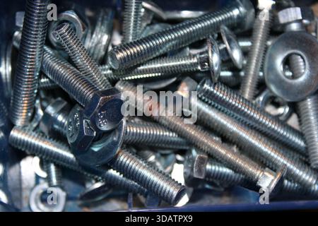 Several metal screws and bolts are placed together in a blue toolbox. The tools are organized and ready for use in various repair tasks in the worksho Stock Photo
