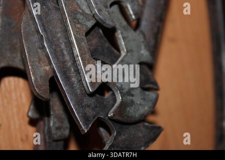 Several metal tools are arranged on a wooden wall. The tools show signs of wear and are used for tasks like repairs and crafting. They hang in differe Stock Photo