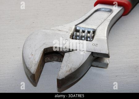 A close view of an adjustable wrench is placed on a white surface. The wrench shows the measuring scale which helps in tightening and loosening variou Stock Photo