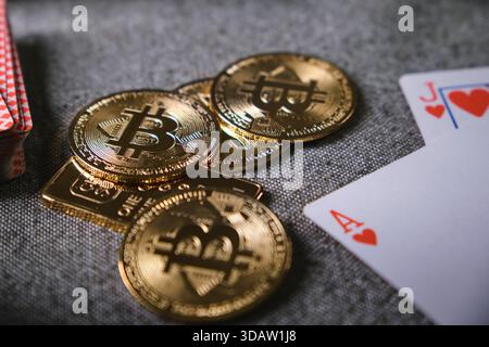 Bitcoin physical coins, gold bar, and playing cards representing cryptocurrency gambling risks Stock Photo