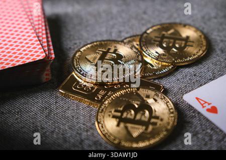 Bitcoin physical coins, gold bar, and playing cards representing cryptocurrency gambling risks Stock Photo