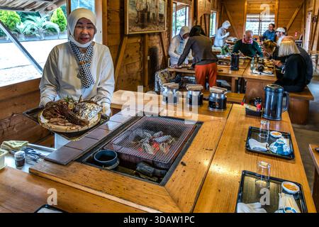 Ama diver Kimiyo Hayashi with fresh seafood, which she prepares on a charcoal stove right in front of the guests. In a replica of a traditional ama hut on the coast of Mie. Shima, Mie, Japan Stock Photo