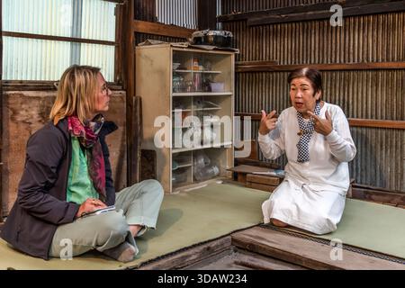 Travel journalist Angela Berg talks with Ama diver Kimiyo Hayashi in the original hut where Hayashi's mother once worked as an Ama. Shima, Mie Prefecture, Japan. Stock Photo