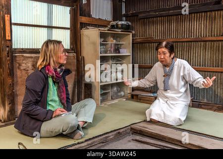 Travel journalist Angela Berg talks with Ama diver Kimiyo Hayashi in the original hut where Hayashi's mother once worked as an Ama. Shima, Mie Prefecture, Japan. Stock Photo
