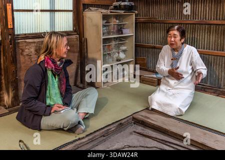Travel journalist Angela Berg talks with Ama diver Kimiyo Hayashi in the original hut where Hayashi's mother once worked as an Ama. Shima, Mie Prefecture, Japan. Stock Photo