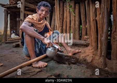Man sharpening an axe on a stone in an Indian village, Odisha, India Stock Photo
