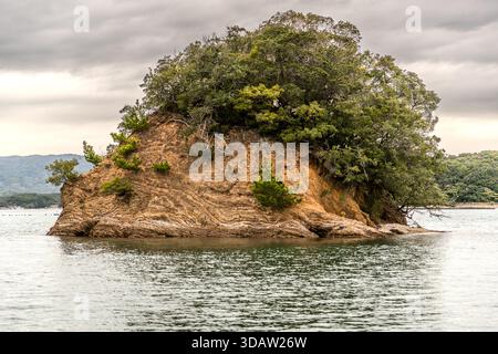 A small, wooded rocky islet with exposed layers of sedimentary rock in Ago Bay, Shima, Mie Prefecture, Japan Stock Photo