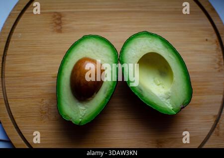 Avocado on a wooden board. Halved avocado. Sliced. Ripe, juicy Stock Photo