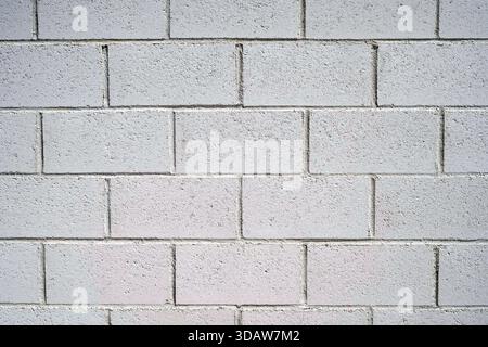 A gray concrete block wall displays a uniform arrangement with visible texture, ideal for modern interiors or industrial designs. It offers a neutral Stock Photo