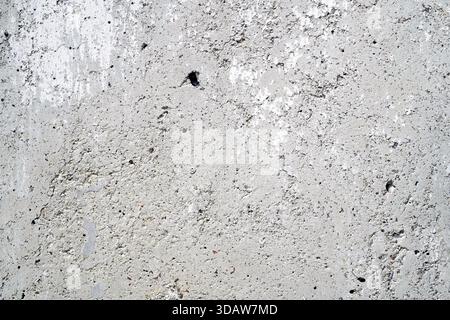 A close-up view of a textured concrete wall displaying various imperfections and wear. Stock Photo