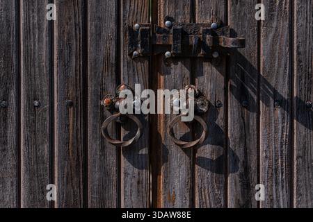 A rustic wooden door in Mtskheta, Georgia, highlights the town's historical charm. The detailed texture and iron accents reflect the ancient architect Stock Photo