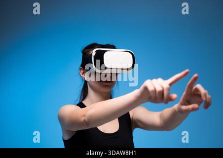 Woman immersed in VR headset experience while interacting with virtual interface using both hands Stock Photo