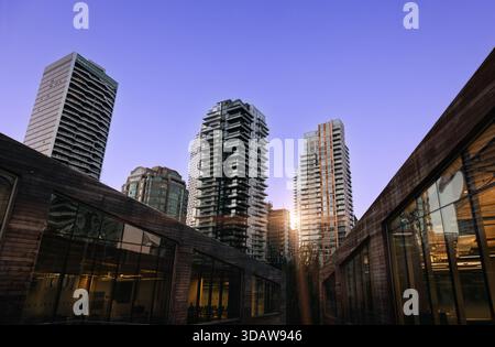 A stunning view of modern skyscrapers in downtown Vancouver, with sleek glass facades reflecting the sky. Urban architecture contrasts with the wooden Stock Photo
