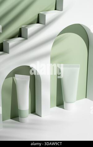 Minimalist scene showcasing cosmetic tubes on geometric podiums. The products are set against an arched backdrop with soft shadows, featuring subtle g Stock Photo