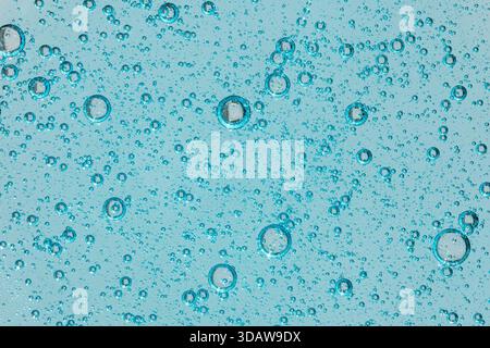 Close-up image of blue cosmetic gel with visible air bubbles on a clear, glossy background. This texture showcases the smooth, translucent quality of Stock Photo