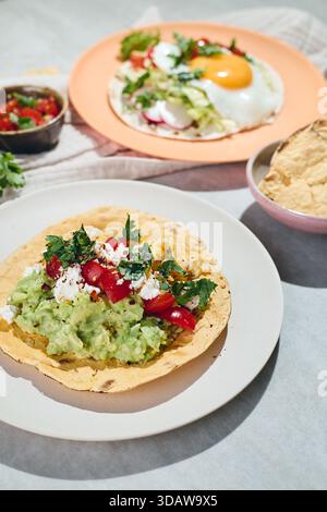 Delicious breakfast tacos with fried eggs and scrambled eggs, guacamole, salsa and cilantro sprinkled. Mexican Breakfast with Huevos Rancheros Stock Photo