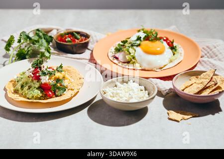 Delicious breakfast tacos with fried eggs and scrambled eggs, guacamole, salsa and cilantro sprinkled. Mexican Breakfast with Huevos Rancheros Stock Photo