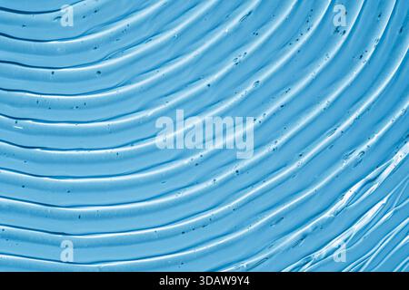 A macro close-up of translucent blue gel texture featuring intricate wavy smears, capturing the detailed clear surface and small air bubbles in a calm Stock Photo