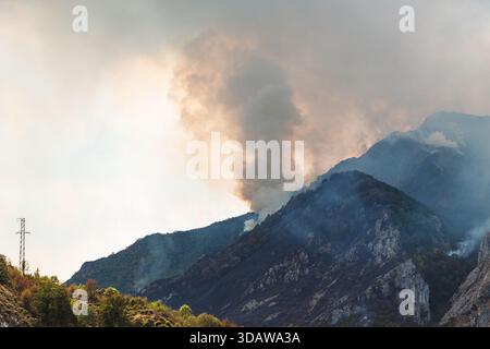 Thick smoke billows from a forest fire in the Somiedo Valley, Asturias, highlighting the impact of environmental disasters in hot summers in northern Stock Photo