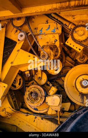 Close up of yellow agricultural machinery components used in farming near Guadalajara, Spain, highlighting intricate gears, chains, and mechanical par Stock Photo
