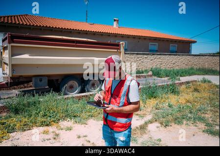 A farmer in Guadalajara, Spain, uses a digital tablet to manage agricultural activities, showcasing the integration of modern technology in traditiona Stock Photo