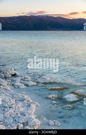 The serene beauty of Lake Salda at sunset, showcasing the unique white stromatolites on the shore. The calm waters beautifully reflect the vibrant sky Stock Photo