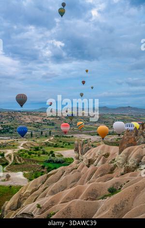 Vibrant hot air balloons float above the unique landscapes of Cappadocia's Red and Rose Valley. The colorful display complements the stunning natural Stock Photo