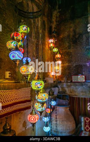 A captivating display of colorful Turkish mosaic lamps illuminates a rustic interior in Cappadocia, Turkey, creating a warm, inviting, and culturally Stock Photo