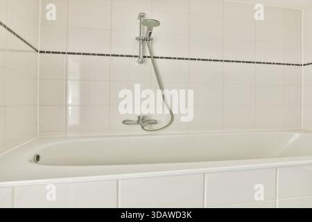 A sleek and contemporary bathroom featuring a freestanding bathtub and minimalist design with clean lines and white tiles. Stock Photo