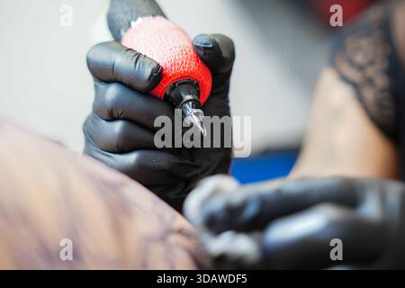 A female tattoo artist works diligently in a tattoo studio, focusing on creating intricate designs on a client’s skin, showcasing skill and precision Stock Photo