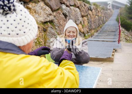 Cheerful older couple dressed warmly, sharing a moment of laughter while enjoying outdoor winter activities. Their joyful expressions radiate warmth a Stock Photo