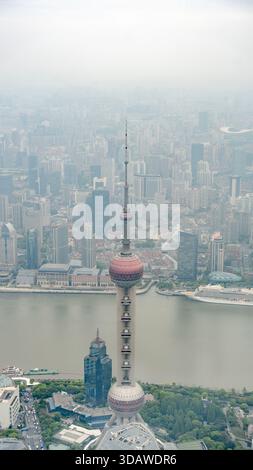 Aerial view of Shanghai skyline featuring the iconic Oriental Pearl Tower amidst a hazy atmosphere, showcasing the blend of modern skyscrapers and urb Stock Photo