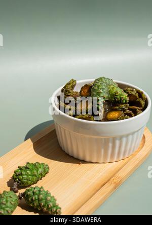 A white ceramic bowl filled with organic pine cone honey sits on a wooden board. The background features a soft green gradient, highlighting the natur Stock Photo