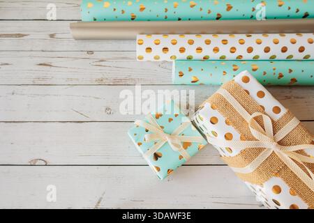 Coordinated gift wrap set with golden hearts and dots on a white wood background. Stylish and cozy packaging flat lay for holidays, celebrations, and Stock Photo